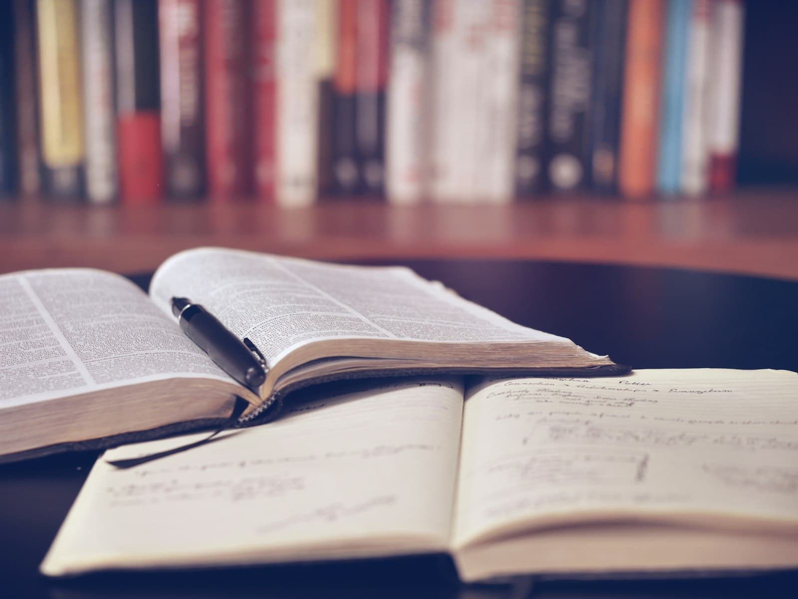 An open notebook with handwritten study notes next to a pen